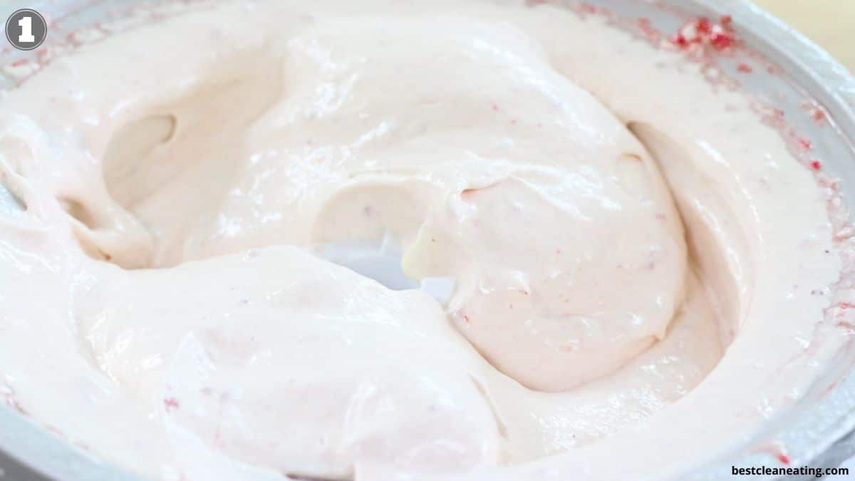A close-up of thick, creamy white mixture with a few small red specks in a mixing bowl.