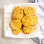 A plate lined with paper towels holds several pieces of golden brown fried food, arranged in a single layer on a light surface.