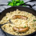 Cast iron skillet filled with sausage sauerkraut.