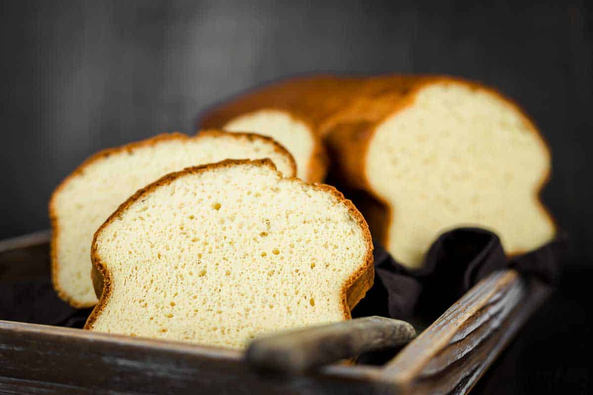 Sliced pieces of brioche bread placed on top of a basket with a half loaf at the back, uncut.