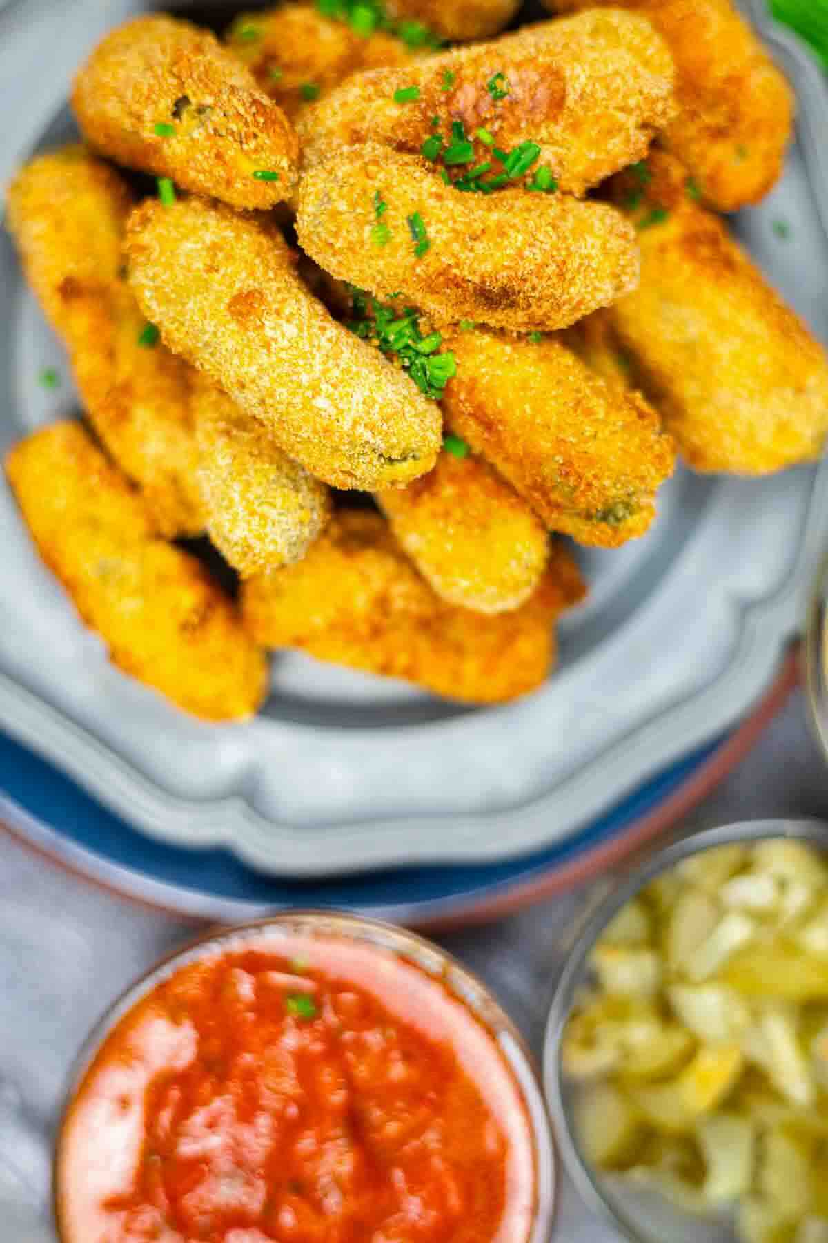 Plate of golden breaded gherkins with dips.