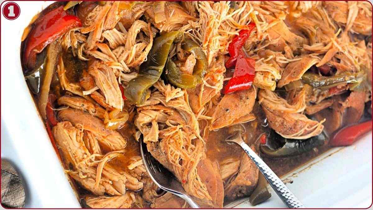 Shredded cooked meat mixed with red and green bell peppers in a brown sauce, served in a white dish with a metal spoon.