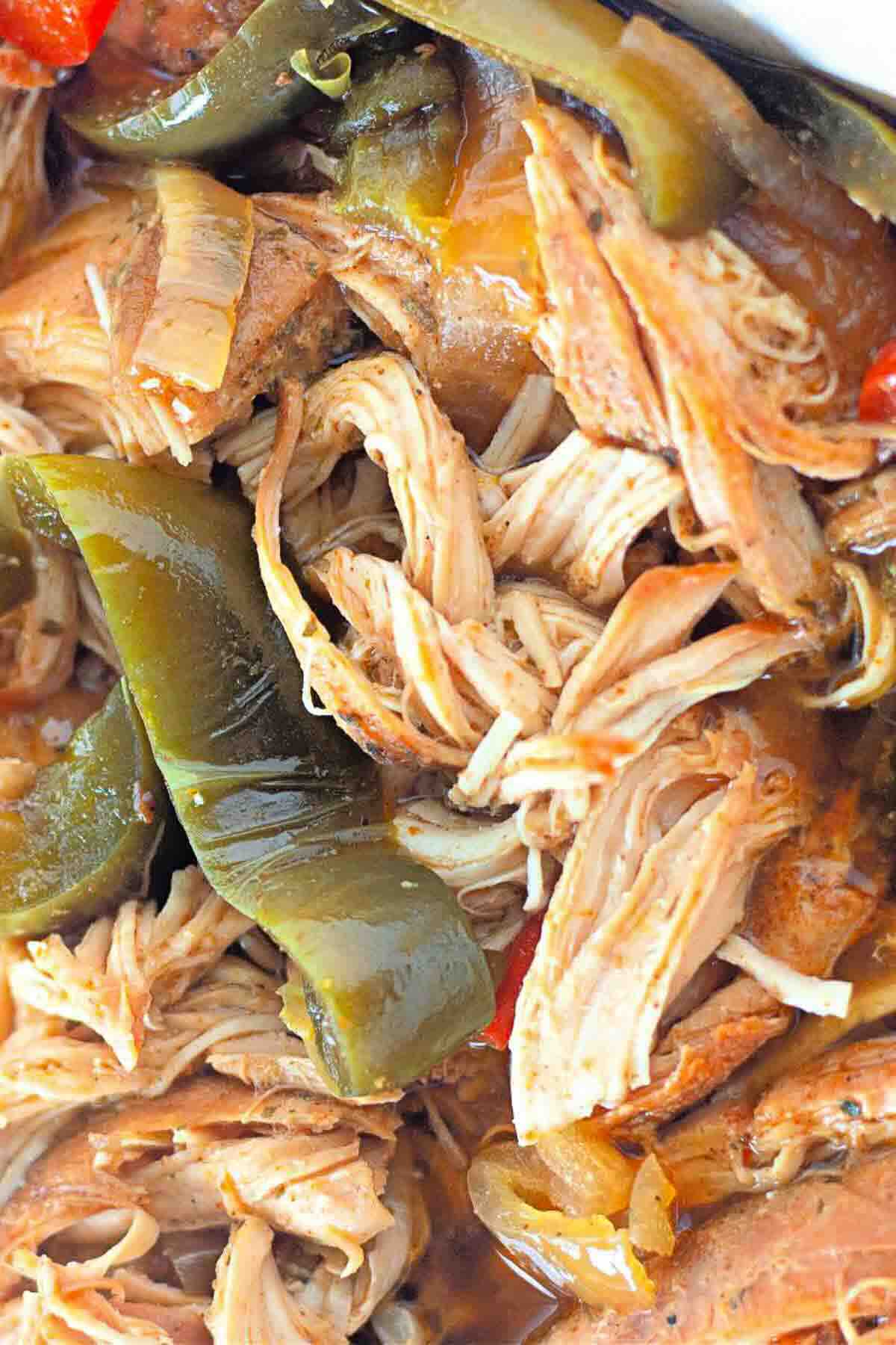 Close-up of shredded cooked meat mixed with sliced green bell peppers and visible sauce.