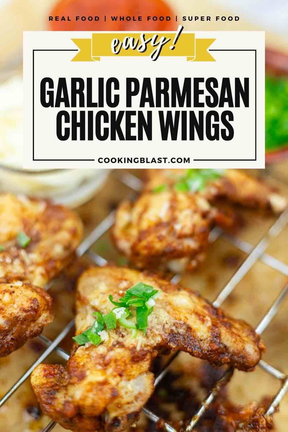 Close-up of garlic parmesan chicken wings on a wire rack, garnished with chopped herbs, with a dipping sauce in the background.