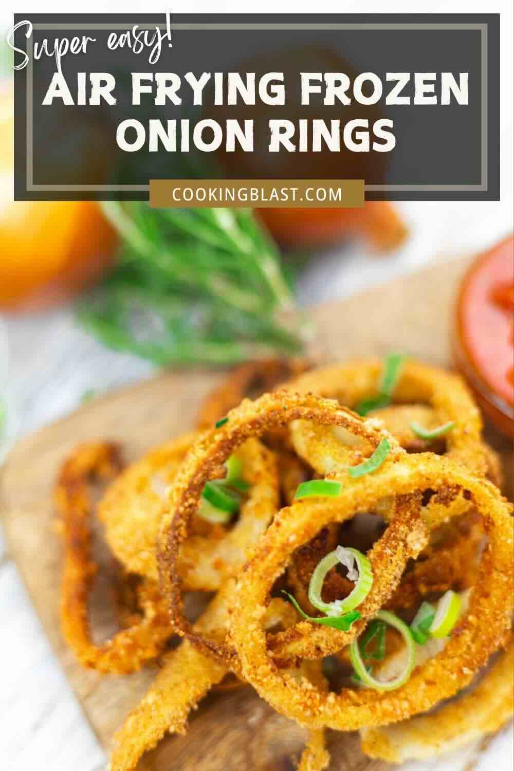 Close-up of crispy air-fried onion rings garnished with green onions, served on a wooden board with dipping sauce in the background. Text overlay reads “Air Frying Frozen Onion Rings.”.