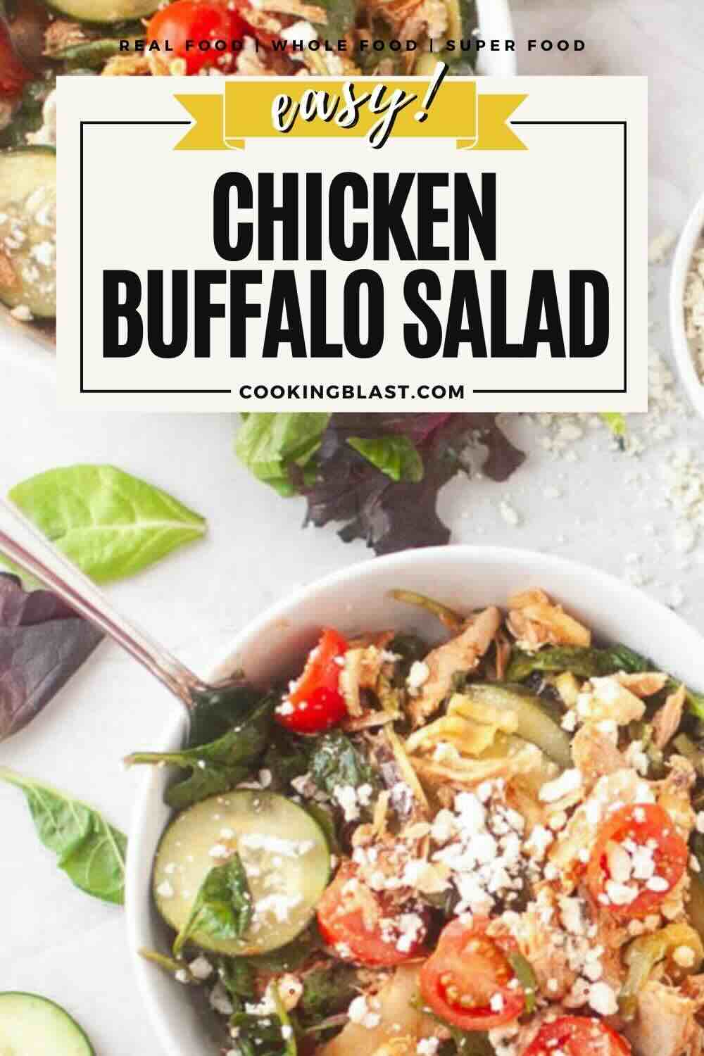 A bowl of chicken buffalo salad with mixed greens, cherry tomatoes, cucumbers, shredded chicken, and feta cheese, next to a fork and loose salad leaves.