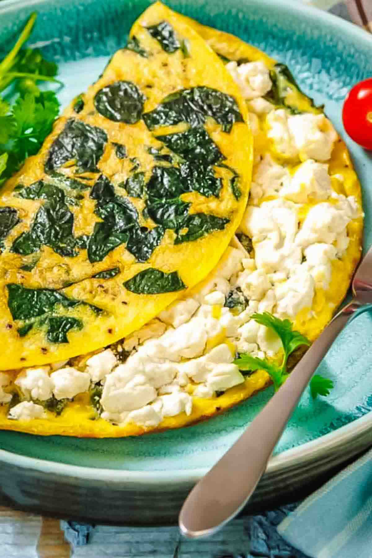 Folded omelet stuffed with crumbled white cheese and spinach on a blue plate.