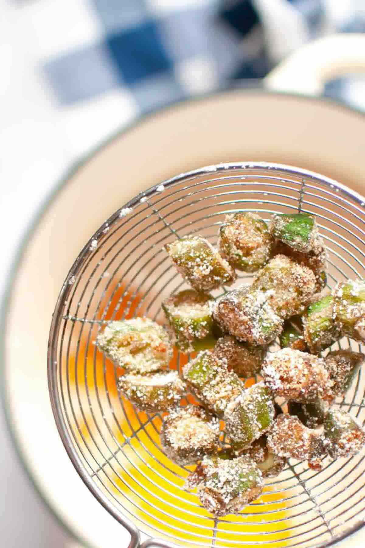 Breaded, fried okra pieces in a wire skimmer.