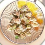 Breaded okra pieces in a wire mesh strainer.
