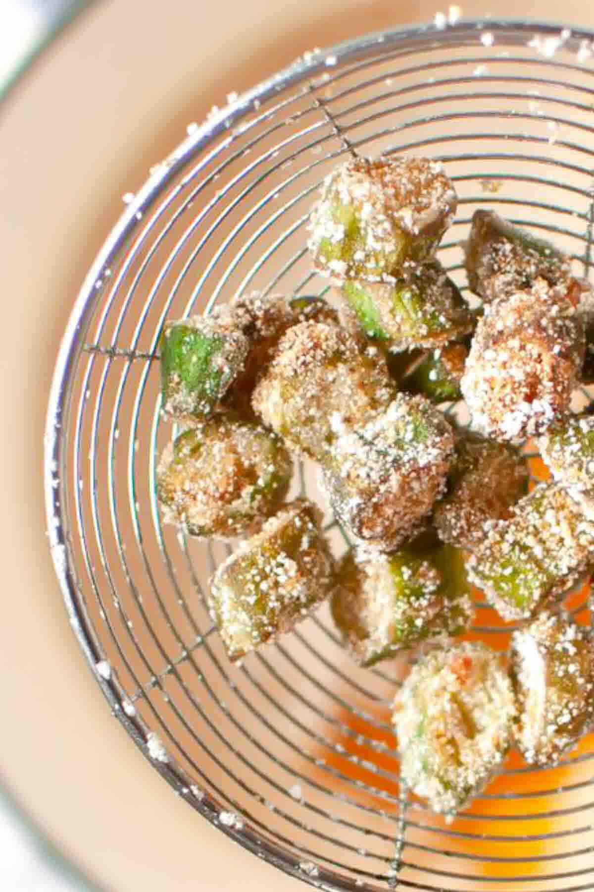 Fried okra pieces in a wire skimmer.