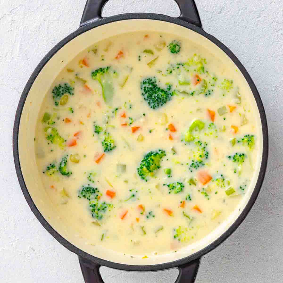 Creamy broccoli and carrot soup in a dark Dutch oven.
